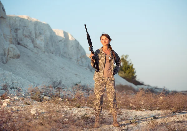 Jovem soldado vestido com uma camuflagem com uma arma no l — Fotografia de Stock