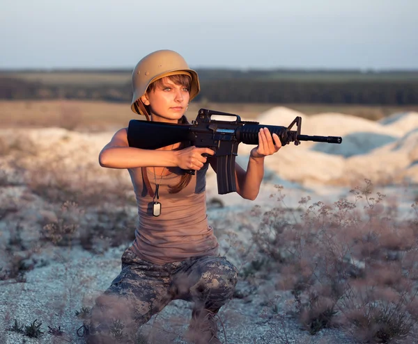 Jovem soldado vestido com uma camuflagem com uma arma no o — Fotografia de Stock