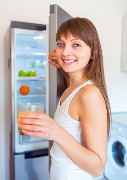 Junge kaukasische Brünette Mädchen mit einem Glas Saft in der Küche — Stockfoto