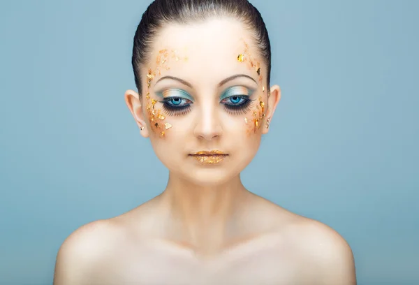 Glamorous portrait of young beautiful girl with big blue eyes, lush lashes and bright golden makeup — Stock Photo, Image