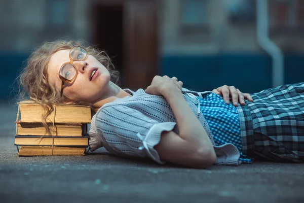 Lustige verrückte Studentin mit Brille, die auf einem Stapel Bücher liegt — Stockfoto