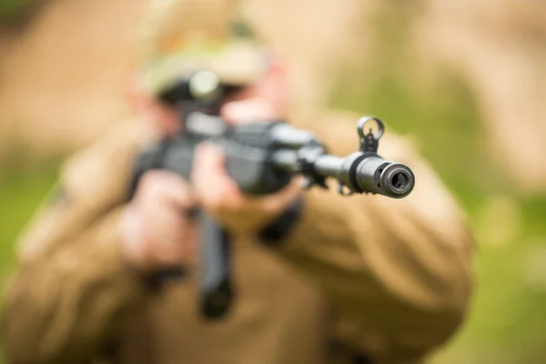 Man in camouflage with a shotgun aiming at a target. Focus on ho — Stock Photo, Image