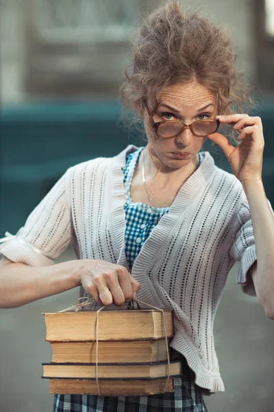 Estudiante divertida chica con libros en gafas y un vestido vintage —  Fotos de Stock