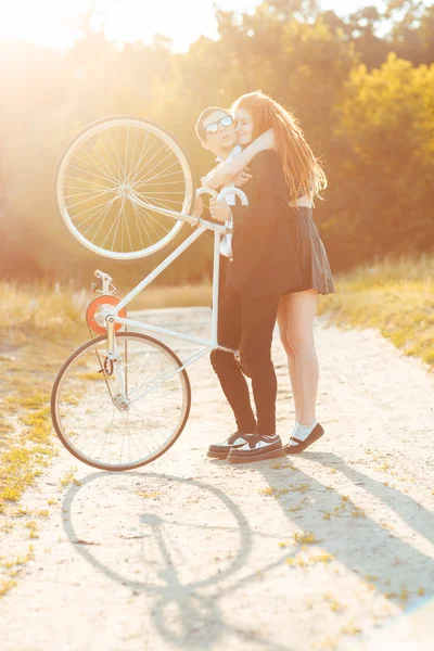 Jovem cara elegante com menina e a bicicleta ao ar livre — Fotografia de Stock