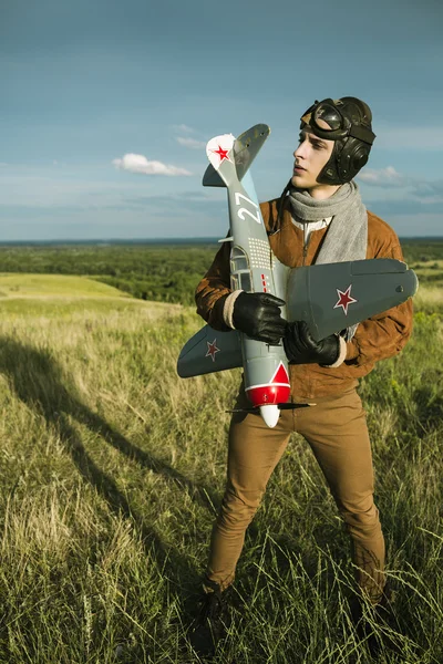 Man in vintage kleding piloot met een vliegtuig model outdoors — Stockfoto