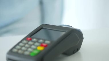 Akıllı telefondan yapılan temassız ödeme. Kablosuz ödeme konsepti. Yakın plan, kadın banka terminalindeki siparişi ödemek için akıllı telefon nakitsiz cüzdan teknolojisi kullanıyor..