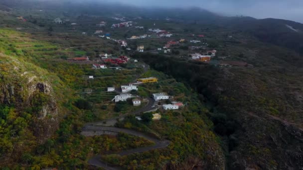 Pohled z výšky na povrchu ostrova Tenerife - horská vesnice, klikatá cesta, mraky nad horami a oceán v dálce. Kanárské ostrovy, Španělsko — Stock video