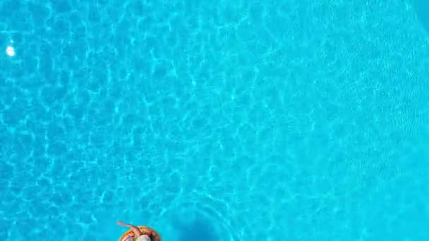 Luftaufnahme einer Frau im gelben Badeanzug, die auf einem Donut im Pool liegt — Stockvideo