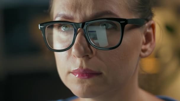 Mujer con gafas mirando en el monitor y navegando por Internet. La pantalla del monitor se refleja en las gafas. Trabaja de noche. Ministerio del Interior. Trabajo remoto — Vídeos de Stock