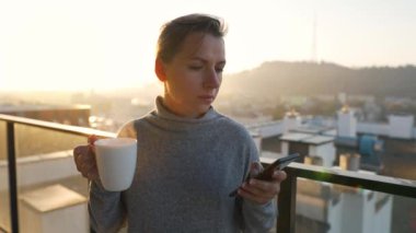 Kadın güne bir fincan çay ya da kahveyle başlıyor ve şafak vakti balkondaki akıllı telefonundaki e-postaları kontrol ediyor..