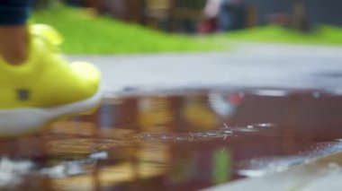 Bayan sporcu kadın dışarıda koşuyor, su birikintisine giriyor. Yağmurda koşan tek koşucu, su sıçratıyor. Yavaş çekim