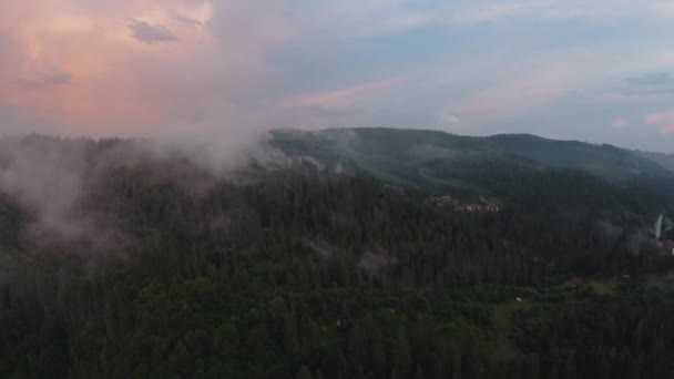 Flight over a mountain resort among the coniferous forest. Mist rises over the mountain slopes — Stock Video