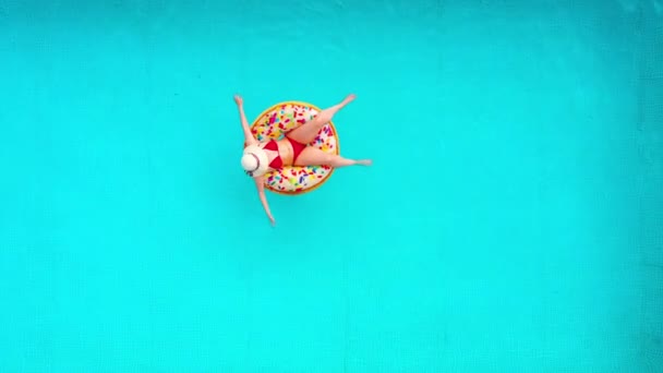 Vista aérea de una mujer en bikini rojo acostada en una dona en la piscina — Vídeos de Stock