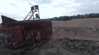FPV insansız hava aracı paslı terk edilmiş kazıcı yakınlarında sorunsuz uçuyor.