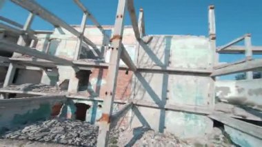 FPV insansız hava aracı, terk edilmiş sanayi binaları ve bir kazıcının etrafında hızla ve manevra kabiliyetiyle uçar..