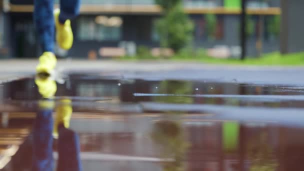 Femme sportive faisant du jogging à l'extérieur, entrant dans la flaque d'eau. Un seul coureur court sous la pluie, faisant des éclaboussures. Mouvement lent — Video