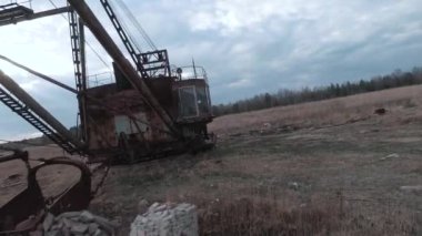 FPV insansız hava aracı paslı terk edilmiş kazıcı yakınlarında sorunsuz uçuyor.
