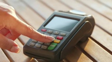 Akıllı telefondan yapılan temassız ödeme. Kablosuz ödeme konsepti. Yakın plan, kadın banka terminalindeki siparişi ödemek için akıllı telefon nakitsiz cüzdan teknolojisi kullanıyor..