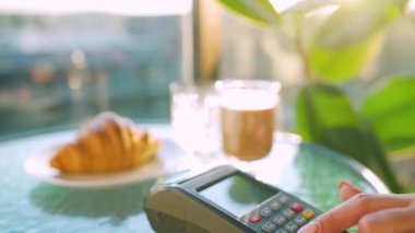 Akıllı telefondan yapılan temassız ödeme. Kablosuz ödeme konsepti. Yakın plan, kadın bir kafedeki banka terminalinin siparişini ödemek için akıllı telefon nakitsiz cüzdan teknolojisi kullanıyor..