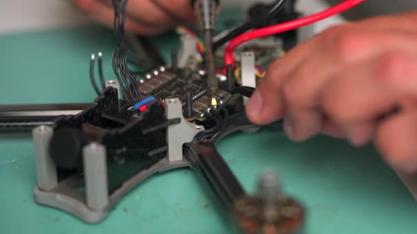 L'homme soude les fils lors de l'assemblage du drone. Construction et restauration du drone FPV — Video
