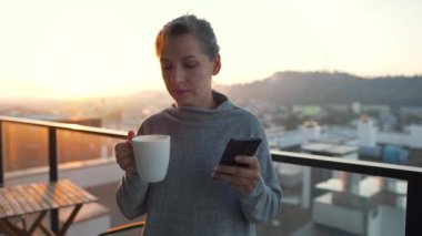 Kadın güne bir fincan çay ya da kahveyle başlıyor ve şafak vakti balkondaki akıllı telefonundaki e-postaları kontrol ediyor..