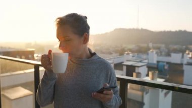 Kadın güne bir fincan çay ya da kahveyle başlıyor ve şafak vakti balkondaki akıllı telefonundaki e-postaları kontrol ediyor..