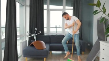 Adam evi temizliyor, dans ediyor ve süpürgeyle şarkı söylüyor. Yavaş çekim
