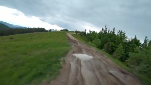 FPV-Video, manövrierbarer Flug mit hoher Geschwindigkeit über einen Feldweg, der am Kamm eines Berges entlang führt. — Stockvideo
