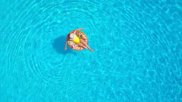 Luftaufnahme einer Frau im gelben Badeanzug, die auf einem Donut im Pool liegt — Stockvideo