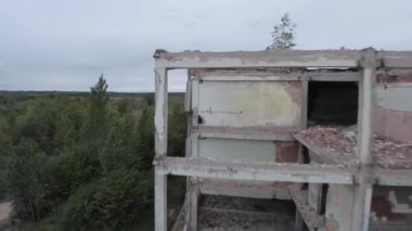 FPV insansız hava aracı, terk edilmiş sanayi binaları ve bir kazıcının etrafında hızla ve manevra kabiliyetiyle uçar..