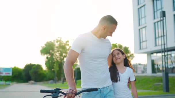 Papa en dochter lopen na zonsondergang rond in hun omgeving. Langzame beweging — Stockvideo