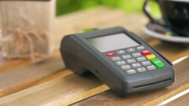 Akıllı telefondan yapılan temassız ödeme. Kablosuz ödeme konsepti. Yakın plan, kadın banka terminalindeki siparişi ödemek için akıllı telefon nakitsiz cüzdan teknolojisi kullanıyor..