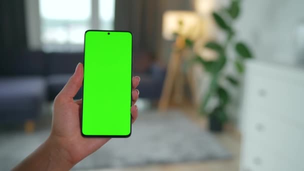 Женщина дома использует смартфон с зеленым макетом экрана в вертикальном режиме. Девушка просматривает Интернет, смотрит контент, видео. POV. — стоковое видео