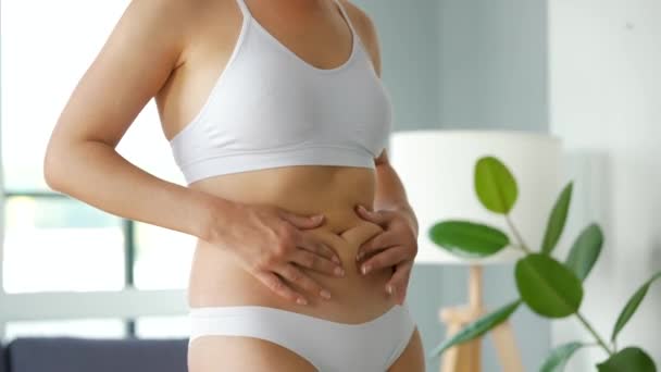 Femme comprimant la peau sur le ventre et les côtés vérifiant la cellulite et l'excès de graisse sous-cutanée — Video