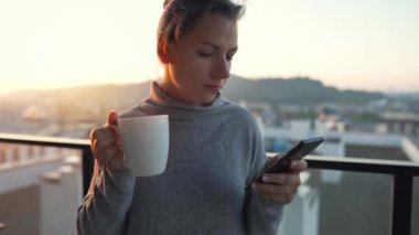 Kadın güne bir fincan çay ya da kahveyle başlıyor ve şafak vakti balkondaki akıllı telefonundaki e-postaları kontrol ediyor..