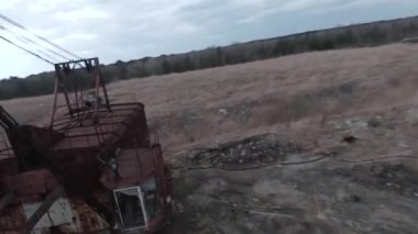 FPV insansız hava aracı paslı terk edilmiş kazıcı yakınlarında sorunsuz uçuyor.