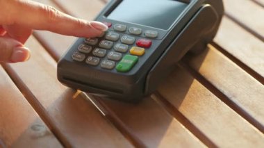 Akıllı telefondan yapılan temassız ödeme. Kablosuz ödeme konsepti. Yakın plan, kadın banka terminalindeki siparişi ödemek için akıllı telefon nakitsiz cüzdan teknolojisi kullanıyor..
