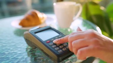 Akıllı telefondan yapılan temassız ödeme. Kablosuz ödeme konsepti. Yakın plan, kadın bir kafedeki banka terminalinin siparişini ödemek için akıllı telefon nakitsiz cüzdan teknolojisi kullanıyor..