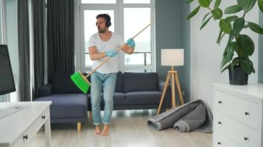 Kulaklıklı adam temizlik yapar ve kendini rock yıldızı olarak hayal eder. Süpürgeyi gitar gibi çalar.