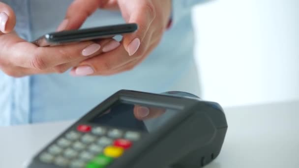 Contactloze betaling met smartphone. Draadloos betaalconcept. Close-up, vrouw met behulp van smartphone cashless portemonnee NFC-technologie om orde te betalen op de bank terminal. — Stockvideo