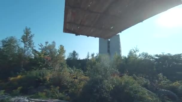 FPV drone vliegt snel en wendbaar tussen verlaten industriële gebouwen en rond een graafmachine. — Stockvideo