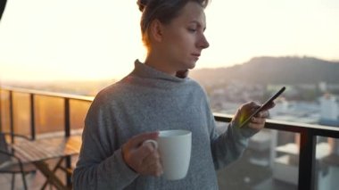 Kadın güne bir fincan çay ya da kahveyle başlıyor ve şafak vakti balkondaki akıllı telefonundaki e-postaları kontrol ediyor..