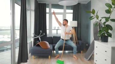 Adam evi temizliyor, dans ediyor ve süpürgeyle şarkı söylüyor.