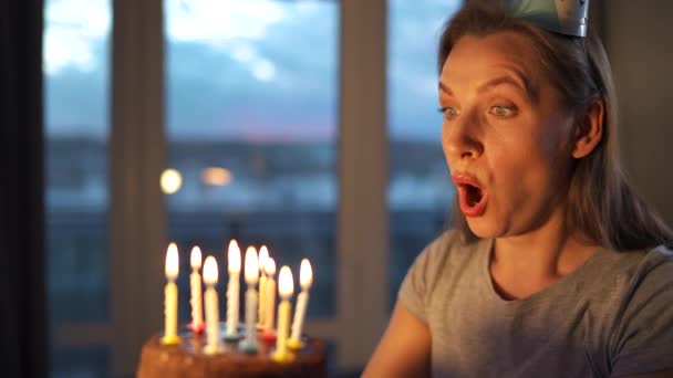 Glücklich aufgeregte Frau macht gehegte Wünsche und bläst Kerzen auf Festtagstorte, feiert Geburtstag zu Hause, Zeitlupe — Stockvideo