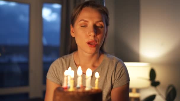 Feliz mulher animada fazendo desejo estimado e soprando velas no bolo de férias, comemorando o aniversário em casa — Vídeo de Stock