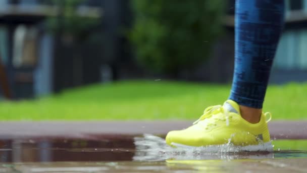 Donna sportiva che fa jogging all'aperto, che entra in una pozzanghera. Singolo corridore che corre sotto la pioggia, facendo schizzi. Rallentatore — Video Stock