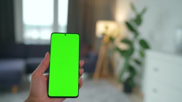 Woman at home using smartphone with green mock-up screen in vertical mode. Girl browsing Internet, watching content, videos. POV. — Stock Video