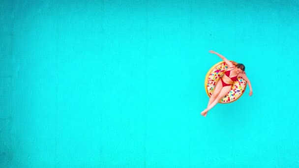 Vista aérea de uma mulher de biquíni vermelho deitada em um donut na piscina — Vídeo de Stock