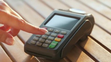 Akıllı telefondan yapılan temassız ödeme. Kablosuz ödeme konsepti. Yakın plan, kadın banka terminalindeki siparişi ödemek için akıllı telefon nakitsiz cüzdan teknolojisi kullanıyor..