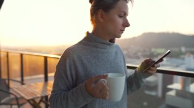 Kadın güne bir fincan çay ya da kahveyle başlıyor ve şafak vakti balkondaki akıllı telefonundaki e-postaları kontrol ediyor..